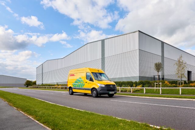 A electric DHL van drives on the street in front of an eCommerce Hub.